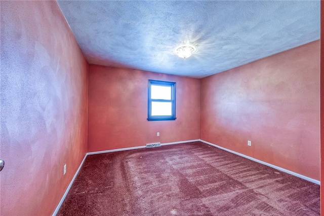 carpeted empty room with visible vents, baseboards, and a textured ceiling