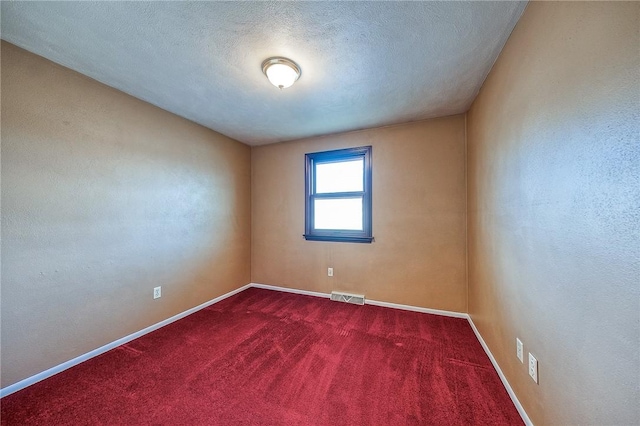 empty room with baseboards, visible vents, dark carpet, and a textured ceiling