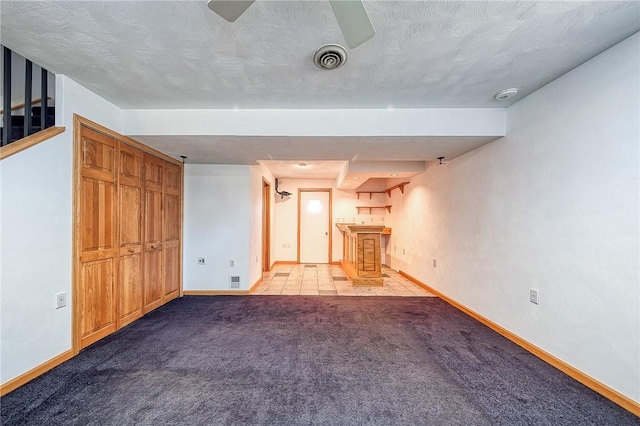 unfurnished living room with visible vents, baseboards, a textured ceiling, and carpet flooring