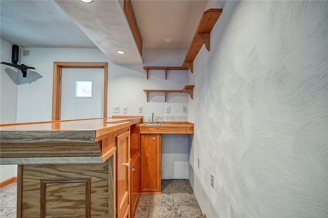 bar featuring stone finish floor, wet bar, and a sink