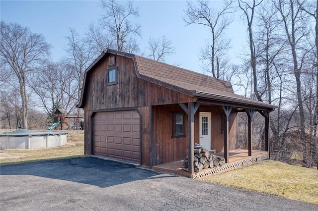 exterior space with a covered pool, an outbuilding, and a porch