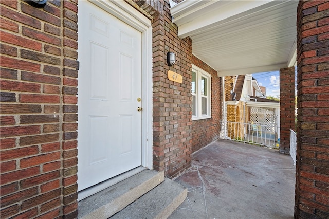 property entrance featuring brick siding and covered porch