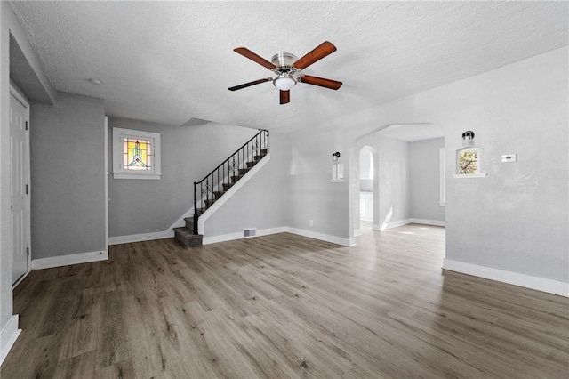 47 Bellanca Ave, Brentwood, PA 15227 - unfurnished living room with visible vents, wood finished floors, arched walkways, baseboards, and stairs