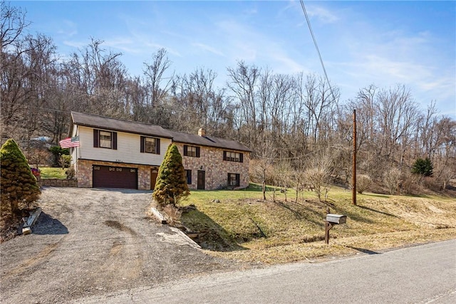 bi-level home with stone siding, driveway, a chimney, and a garage