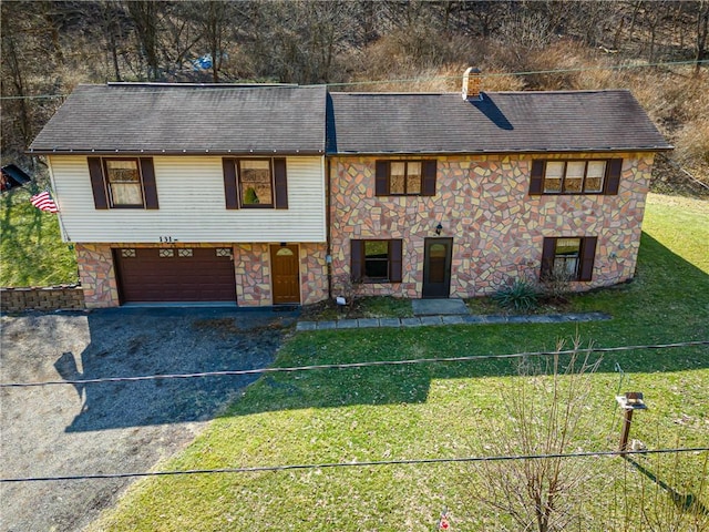 view of front of home featuring a front yard, fence, driveway, a garage, and stone siding