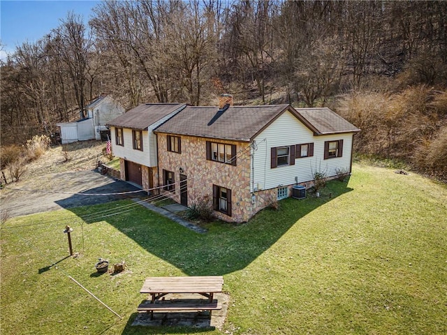 exterior space with a yard, central AC unit, a garage, and a chimney