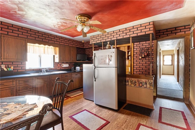 kitchen featuring a sink, light wood-style floors, dark countertops, and freestanding refrigerator