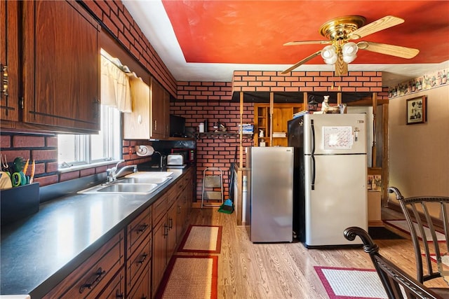 kitchen featuring dark countertops, light wood-style flooring, freestanding refrigerator, and a sink