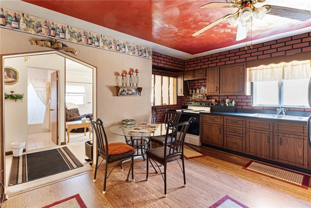 interior space featuring ceiling fan, brick wall, and light wood finished floors