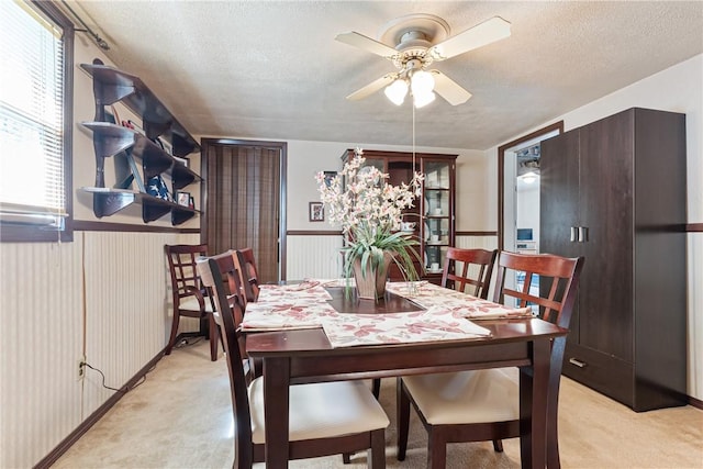 dining room featuring light carpet, a wainscoted wall, and a textured ceiling