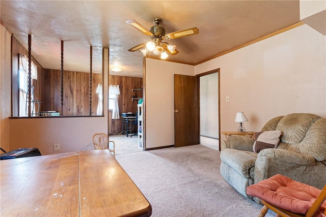 interior space featuring carpet, wood walls, a ceiling fan, and a textured ceiling