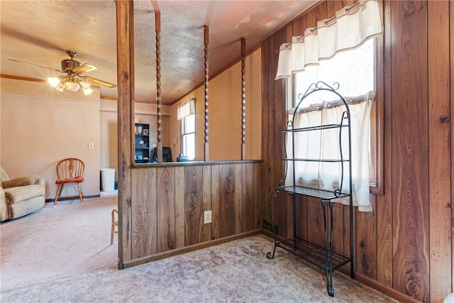 kitchen featuring a ceiling fan, wood walls, and carpet flooring