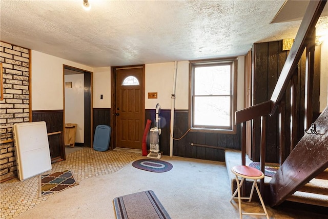 interior space with stairway, a wainscoted wall, and a textured ceiling