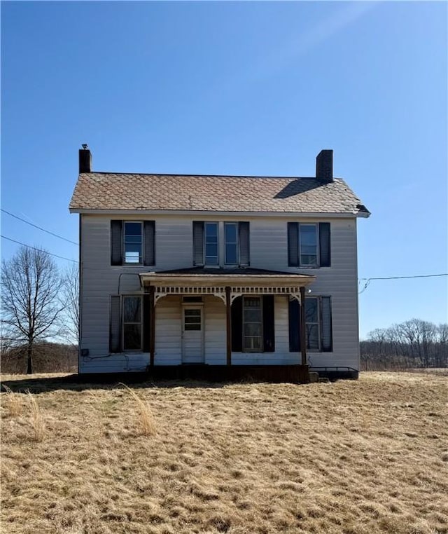 rear view of house featuring covered porch and a chimney