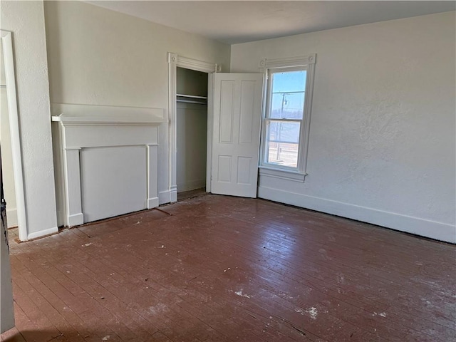 unfurnished bedroom featuring baseboards, wood-type flooring, and a closet