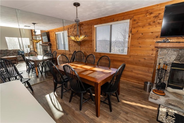 dining area with wood walls, a fireplace, and wood finished floors