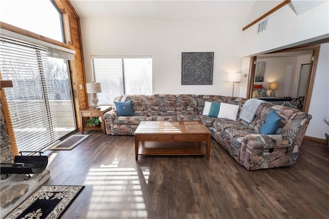 living room with wood finished floors, visible vents, and a towering ceiling