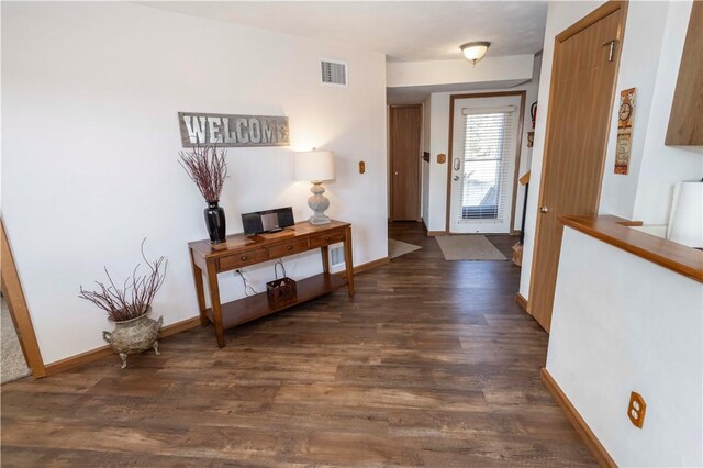 foyer with visible vents, baseboards, and dark wood-style flooring