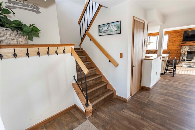 stairway with a fireplace, wood finished floors, and baseboards