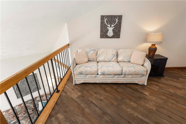 living area featuring vaulted ceiling, baseboards, and wood finished floors