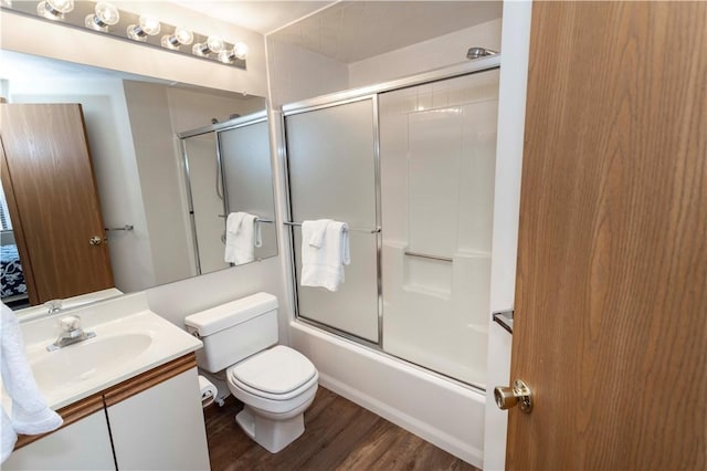 bathroom featuring combined bath / shower with glass door, toilet, vanity, and wood finished floors