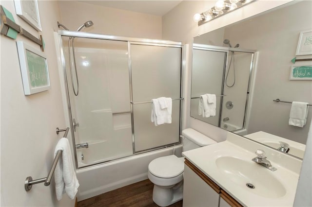 bathroom with wood finished floors, toilet, vanity, and shower / bath combination with glass door