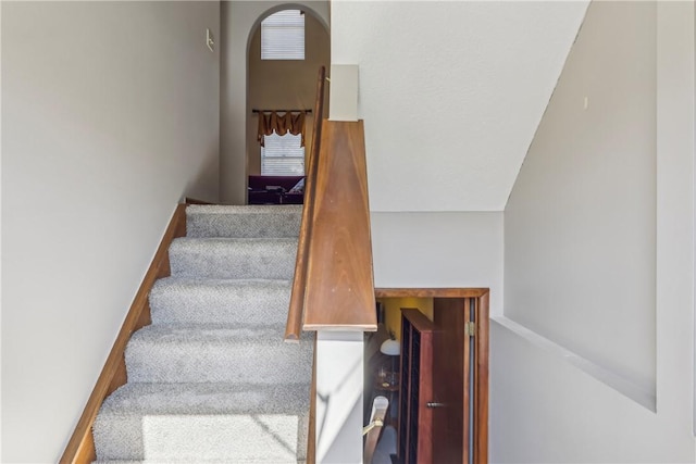 stairway featuring arched walkways and baseboards