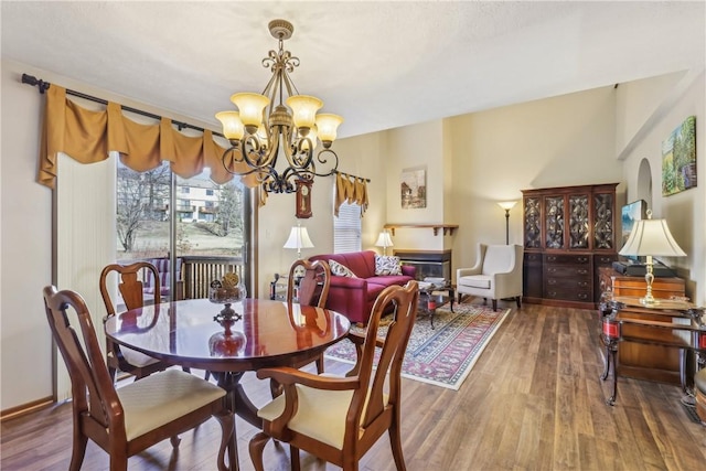 dining room with a glass covered fireplace, a chandelier, and wood finished floors