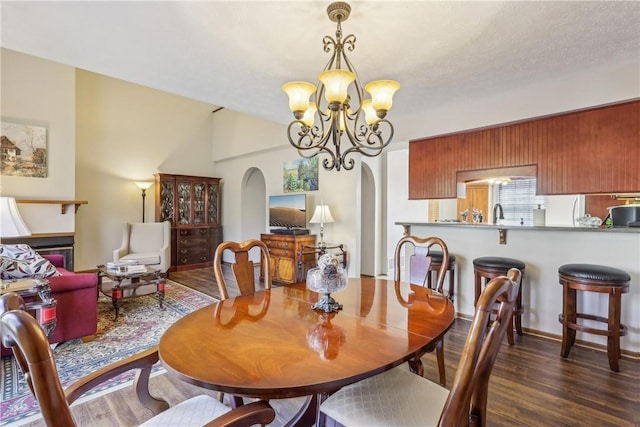 dining room featuring arched walkways, a notable chandelier, and wood finished floors