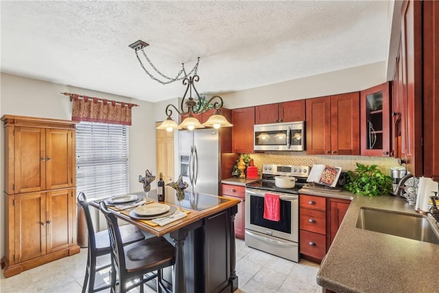 kitchen featuring decorative backsplash, a sink, a textured ceiling, stainless steel appliances, and glass insert cabinets