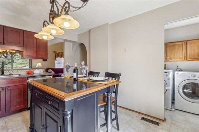 kitchen with visible vents, a center island, pendant lighting, independent washer and dryer, and a sink