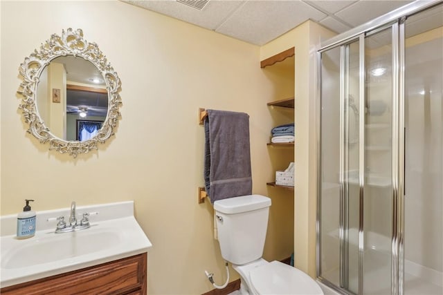 full bath featuring a paneled ceiling, toilet, vanity, and a shower stall