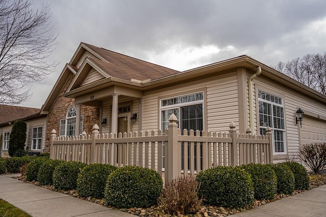 view of side of home featuring a garage and a fenced front yard