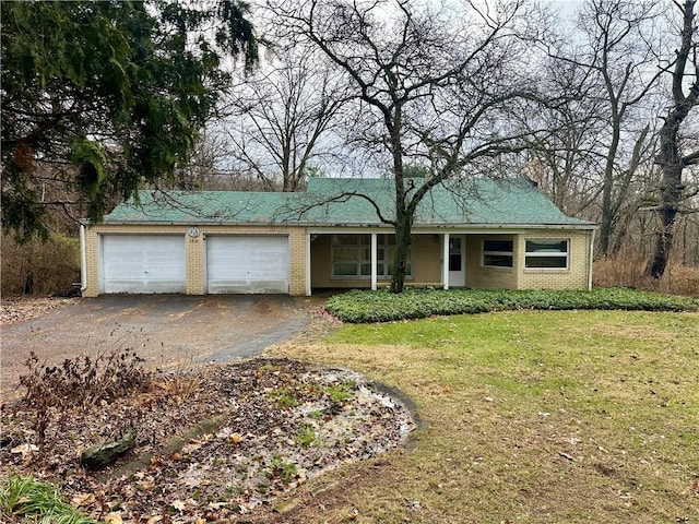 single story home with a front lawn, an attached garage, brick siding, and driveway