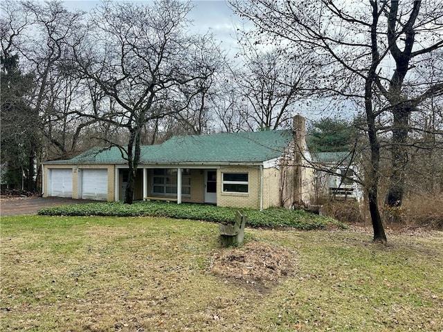 view of front facade featuring a chimney, a front lawn, a garage, aphalt driveway, and brick siding