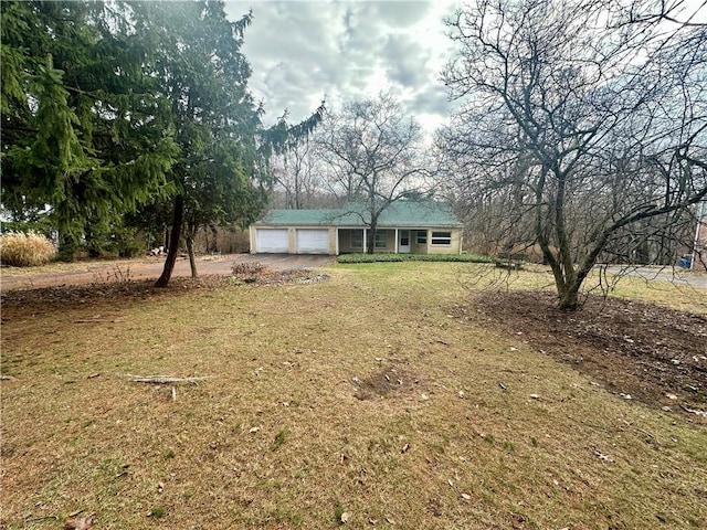 view of front of property with a front lawn, an attached garage, and dirt driveway