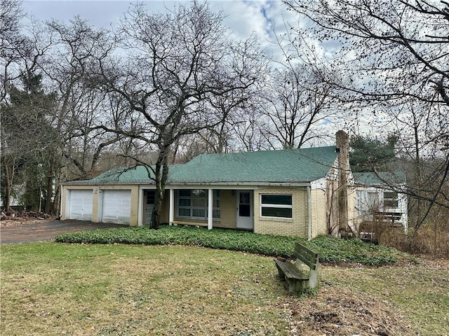 view of front of house with aphalt driveway, brick siding, an attached garage, and a front yard