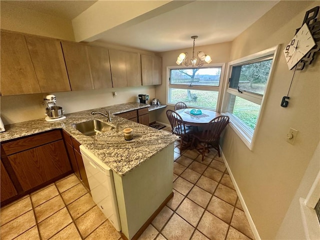 kitchen with light stone countertops, baseboards, a sink, dishwasher, and a notable chandelier