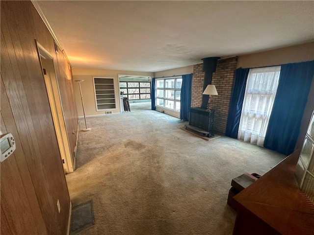 carpeted living room featuring wood walls and a wood stove