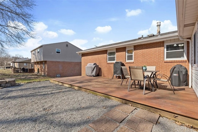 exterior space with outdoor dining area, brick siding, and a deck