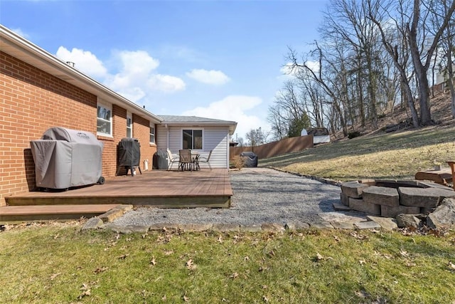 exterior space featuring a wooden deck, brick siding, a yard, and fence