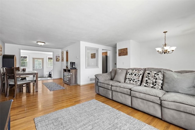 living room with a notable chandelier, visible vents, and light wood-style floors