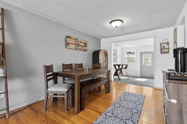 dining room featuring light wood-style flooring, baseboards, and arched walkways