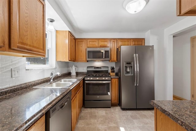 kitchen with dark countertops, tasteful backsplash, brown cabinets, stainless steel appliances, and a sink