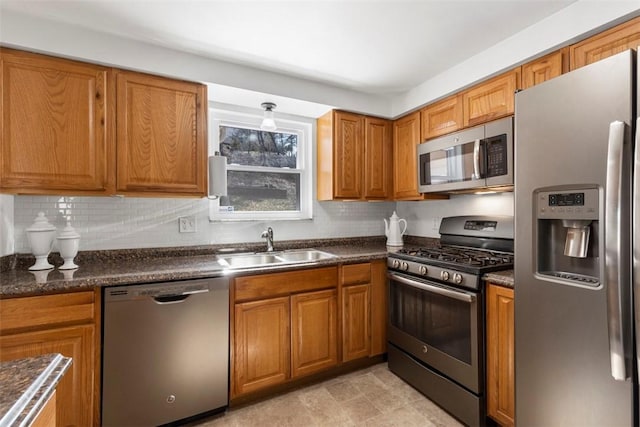 kitchen featuring a sink, dark countertops, appliances with stainless steel finishes, and brown cabinetry