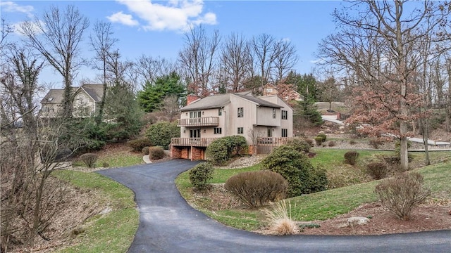 exterior space with a balcony, a chimney, and driveway