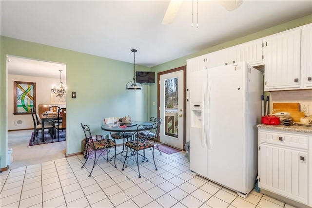 kitchen with light countertops, white cabinets, white fridge with ice dispenser, decorative light fixtures, and a notable chandelier