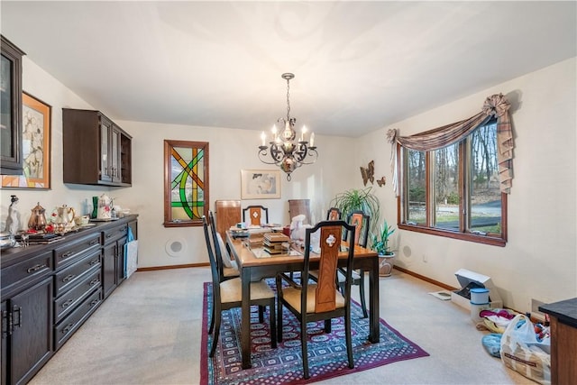 dining area with an inviting chandelier, light colored carpet, and baseboards