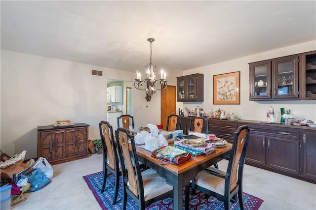 dining space featuring visible vents, light carpet, and a notable chandelier