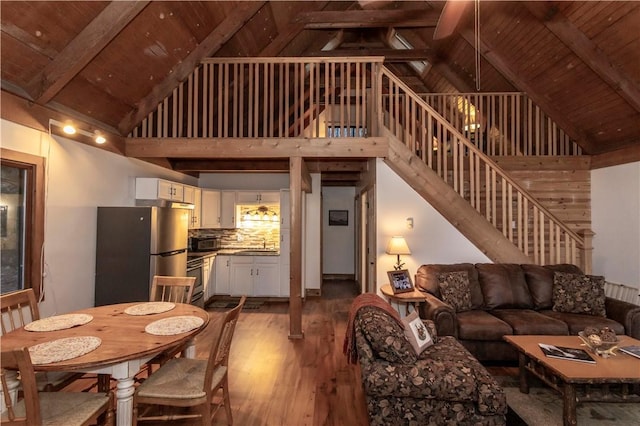 living room featuring stairway, wood finished floors, high vaulted ceiling, wooden ceiling, and beamed ceiling